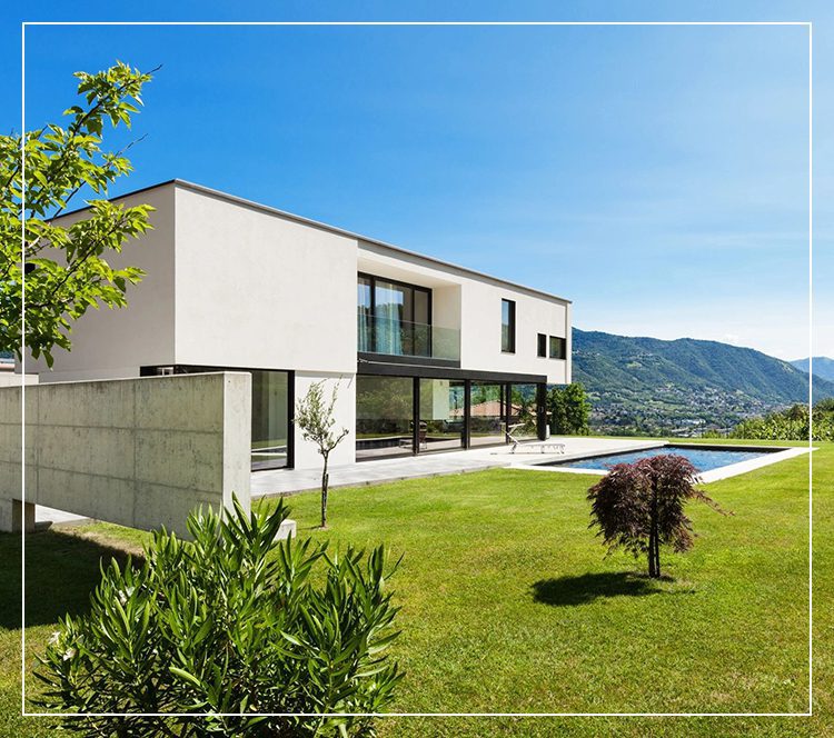 Modern white house with a spacious lawn and mountain view.