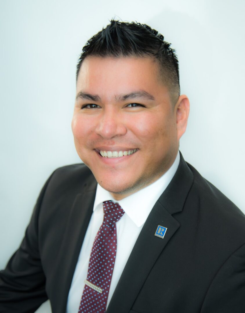 Professional headshot of a smiling man in a suit and tie.